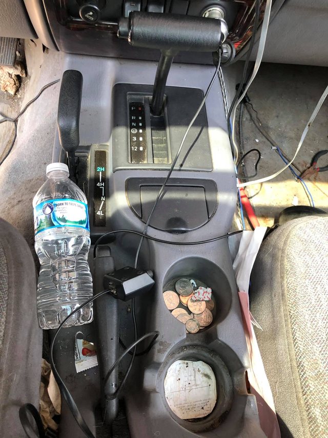 Centre console and shifter area before cleaning, with loose change, a water bottle and grime built up in the cup holders.